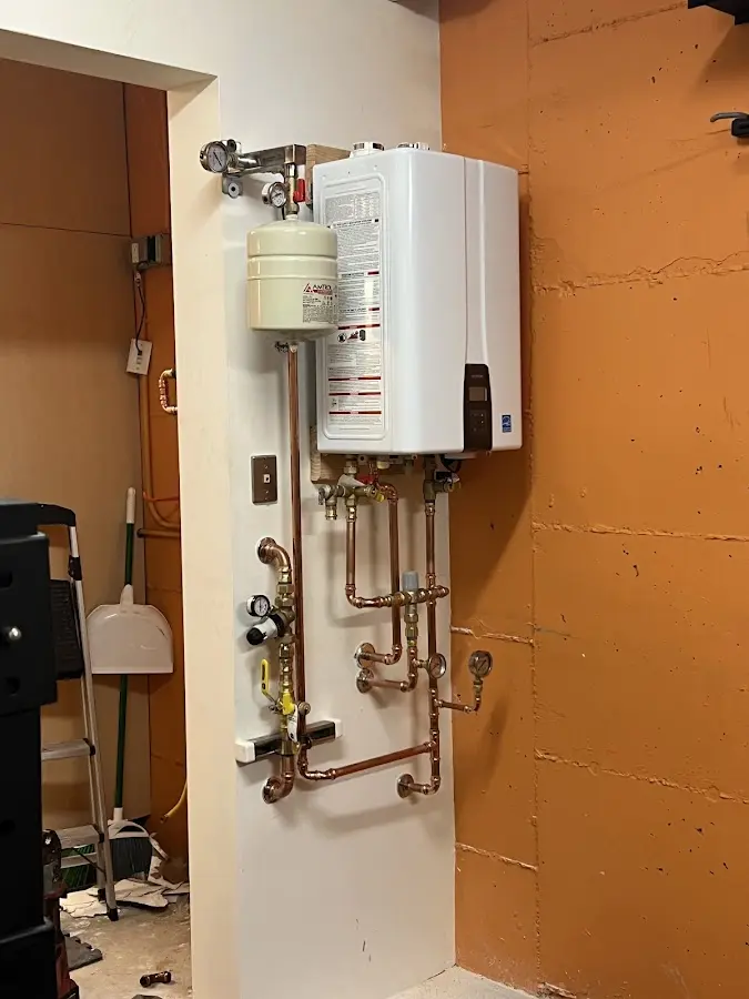 Plumbing technician inspecting water heater connections in Duxbury